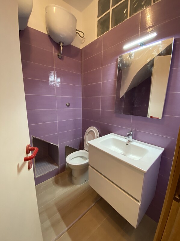 Un baño con azulejos morados, un lavabo blanco y un inodoro.