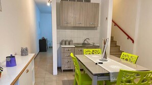 A compact kitchen with a dining area, featuring a table with chairs, a sink, and cabinets.