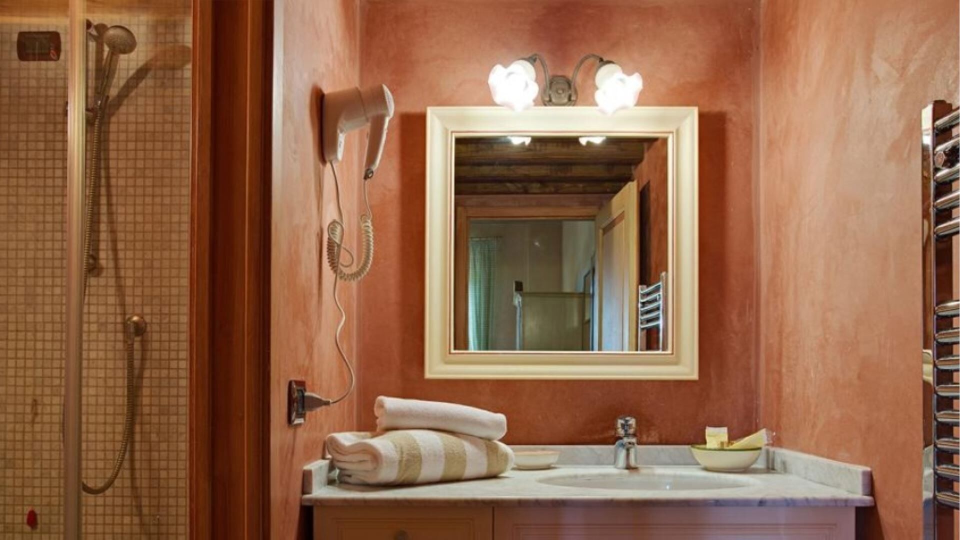 A bathroom with a wooden vanity, a mirror, a shower, and a towel rack.