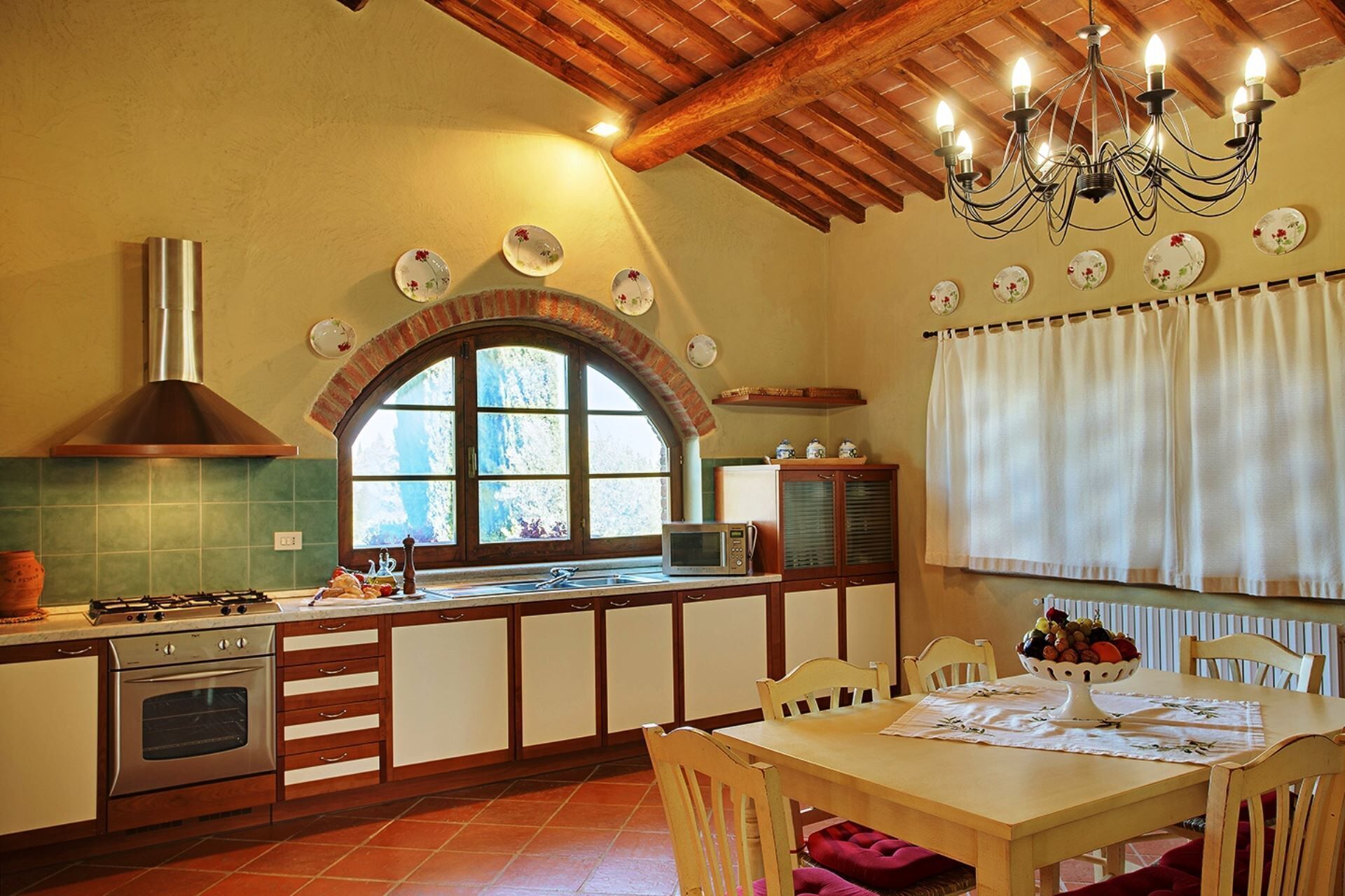 A kitchen with a stove, oven, microwave, and a dining area with a table and chairs.