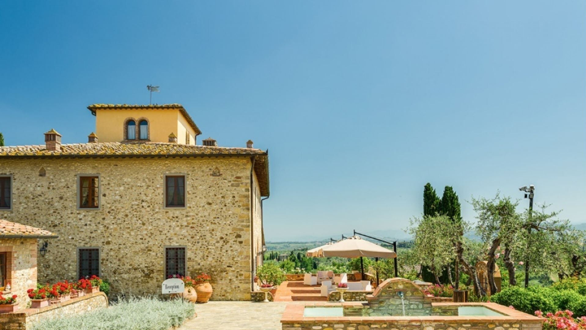 A stone building with a terrace, outdoor seating, and a pool.