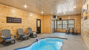 En stuga med träpanel på insidan, en pool, Adirondack-stolar och ett bord vid fönstret.