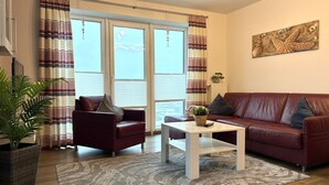 A living room with a red leather sofa, a white coffee table, and a striped rug.