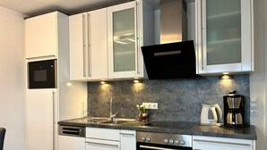 A modern kitchen with white cabinets, a Bosch oven, a sink, and a coffee maker.