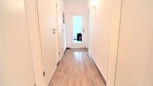 Ein schmaler Korridor mit Holzdielen und weißen Wänden.