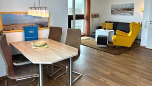 Habitación de hotel moderna con comedor, sofá y vista a la playa.