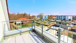 Balcón con baranda de metal que da vista a una zona residencial con casas y un parque infantil.