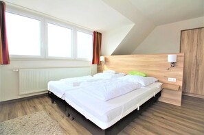 Une chambre à coucher avec un grand lit, une tête de lit en bois, un radiateur et une fenêtre avec des rideaux.