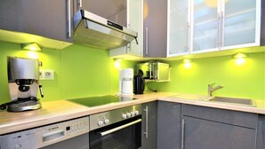 Una cocina compacta con lavavajillas Bosch, cafetera, microondas y un lavabo.