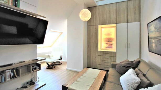 Una sala de estar moderna con un televisor de pantalla plana, una mesa de centro de madera, un sofá y un mueble con un cuadro enmarcado.