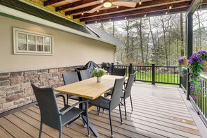 A covered patio with a wooden table and chairs, a potted plant, and a view of trees. - Poconos Cottage w/ Sauna ~ 10 Mi to Camelback! (Tobyhanna)