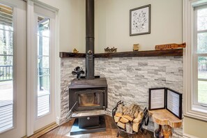 Une cheminée en pierre avec une cheminée noire, une enseigne fixée au mur et un porte-bois.