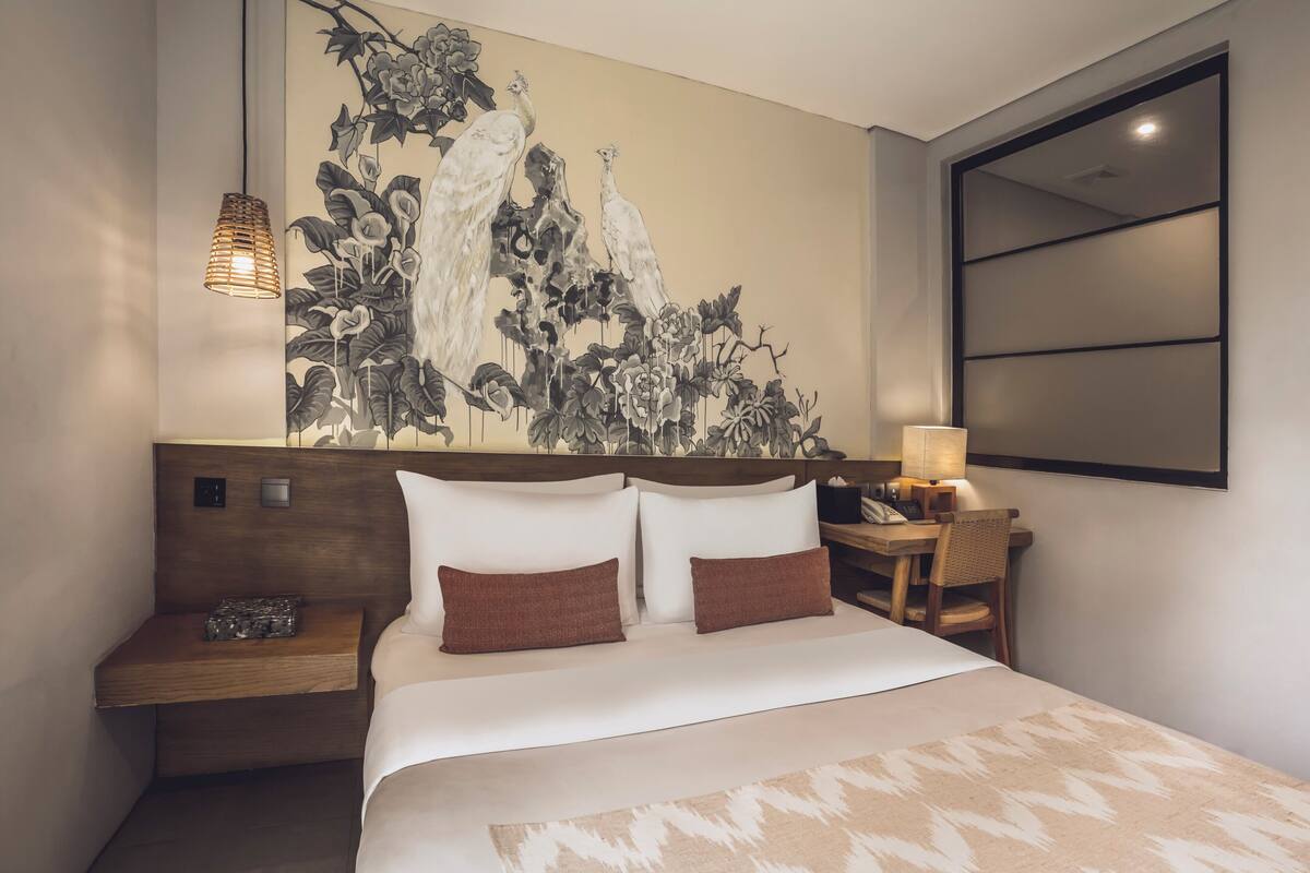A modern hotel room with a large bed, a nightstand, a lamp, and a wall-mounted TV.