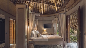 A bedroom with a canopy bed, a flat-screen TV, and a patterned floor. - Amarea Resort & Spa Ubud by iNi Vie Hospitality (Ubud)