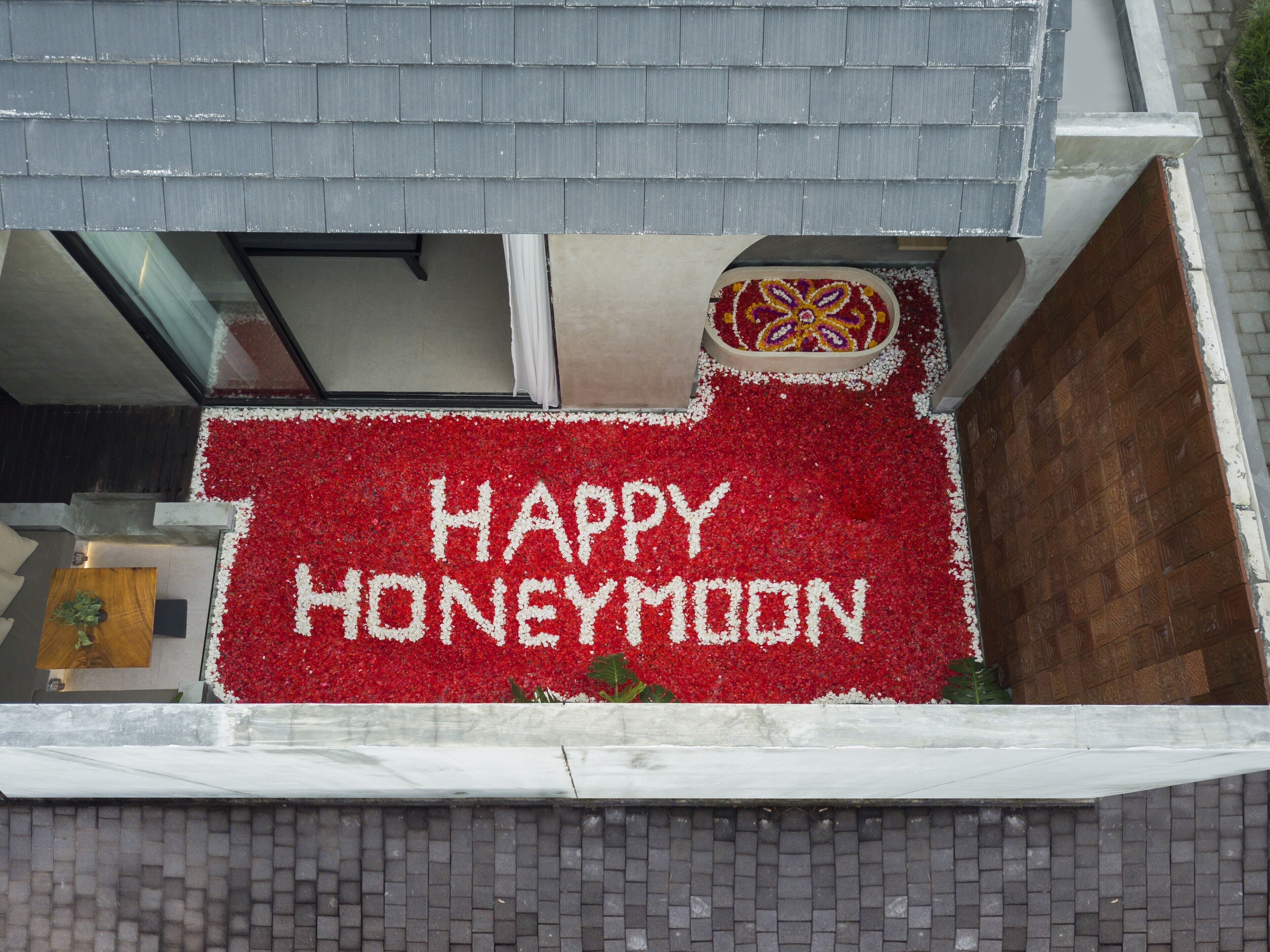 A balcony with a red flower arrangement spelling "HAPPY HONEYMOON" and a decorative item above it.