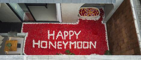 A balcony with a red flower arrangement spelling "HAPPY HONEYMOON" and a decorative item above it.