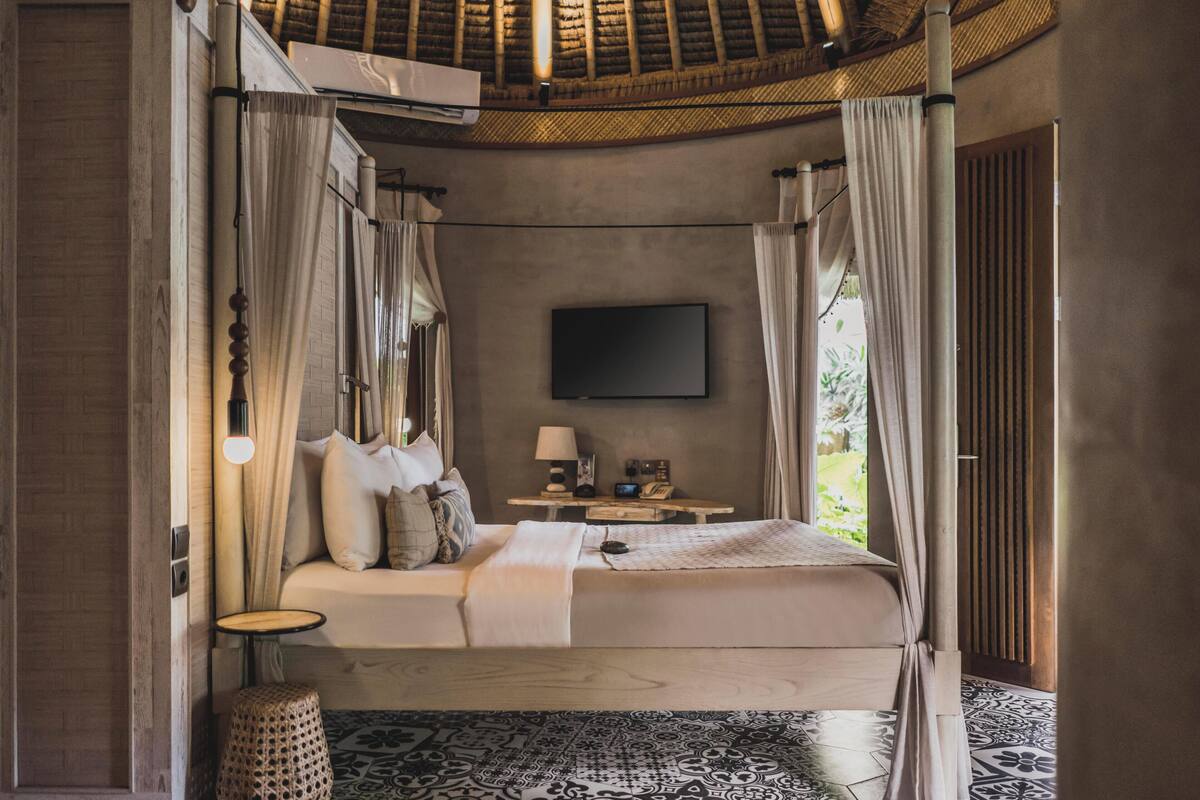 A bedroom with a bed, bedside table, lamp, and a TV.