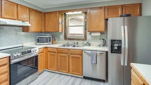 A modern kitchen with wooden cabinets, stainless steel appliances, a microwave, and a built-in oven.