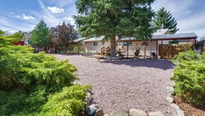 A residential property with a gravel driveway, a covered patio, and a basketball hoop.
