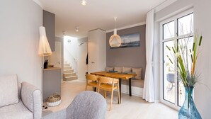 Un salon moderne avec un canapé, une table à manger et un vase de fleurs.