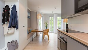 Une cuisine moderne avec un coin repas, un plancher en bois et une vue sur la verdure environnante.