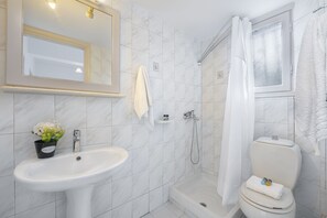 A bathroom with a sink, mirror, shower, and toilet. - Pyrgaraki Studios and Apartments (Zakynthos)