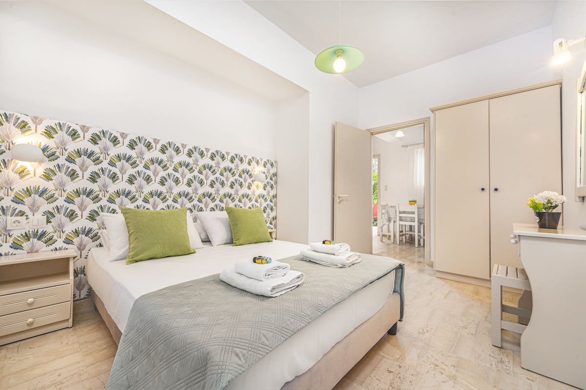 Ein modernes Schlafzimmer mit einem großen Bett, einem Blattmuster-Kopfende, einem Nachttisch und einem Kleiderschrank.