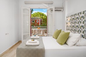 A bedroom with a bed, pillows, and a view of a balcony with a table and chairs. - Pyrgaraki Studios and Apartments (Zakynthos)