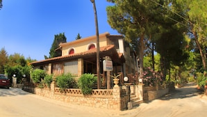 A two-story building with a stone facade, a red-tiled roof, and a sign indicating it houses studios and apartments. - Pyrgaraki Studios and Apartments (Zakynthos)