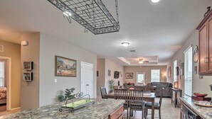 Una cocina amplia con encimeras de granito, armarios de madera y una zona de comedor con sofá gris.