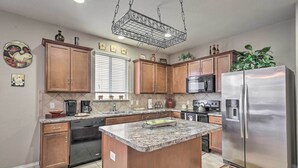 Una cocina con armarios de madera, electrodomésticos de acero inoxidable y encimera de granito.