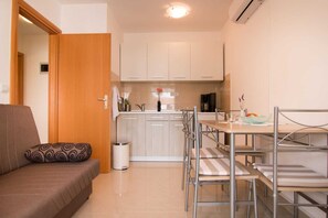 Cozy living space with a kitchenette, sofa, dining table, and coffee machine.