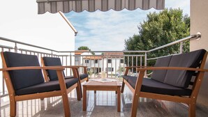 A balcony with two wooden chairs and a small table, a railing, and a building in the background. - Apartment 2124/39598 (Istria - Valbandon), 800m from the beach (Valbandon)