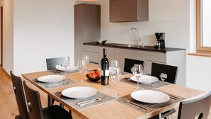 A dining area with a wooden table set for four, equipped with plates, cutlery, and wine glasses. - Apartment 'Torgglbauer 1' with Mountain View, Pool, Terrace & Wi-Fi (Meran)