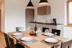 A dining area with a wooden table set for four, equipped with plates, cutlery, and wine glasses. - Apartment 'Torgglbauer 1' with Mountain View, Pool, Terrace & Wi-Fi (Merano)