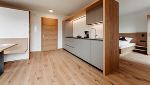 A modern kitchen with wooden cabinetry, a built-in bench, and a small dining area. - Holiday Apartment "Torgglbauer 2" with Mountain View, Pool, Terrace & Wi-Fi (Meran)