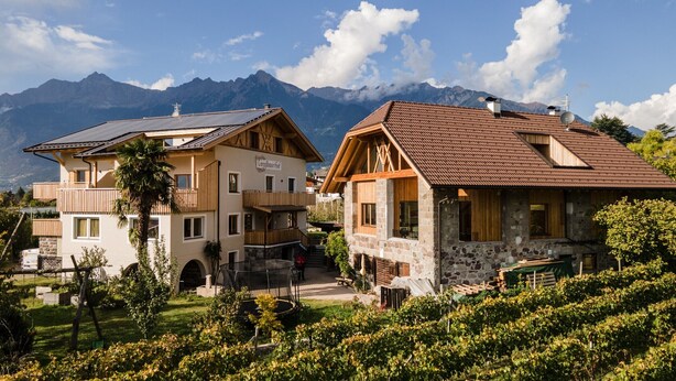 Ein Hotel mit einer Stein-Fassade, hölzernen Balkonen und Blick auf die Berge.