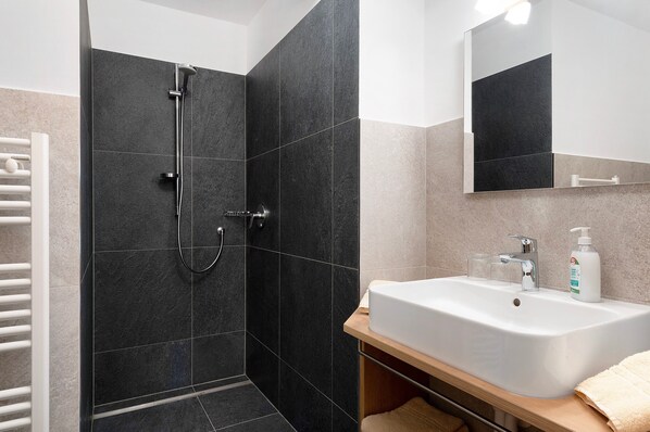 A modern bathroom with a shower, sink, and mirror.
