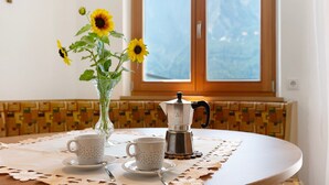 Taula amb una cafetera, dues tasses i un vas amb gessamí.