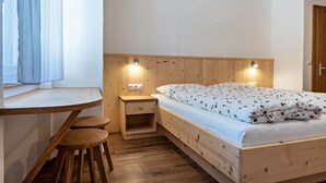 A wooden bed with a headboard, bedside tables, a small desk, and stools. - Holiday Apartment 'Thusnelda A' with Mountain View, Balcony & Wi-Fi (Seis am Schlern)