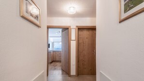 Un pasillo con una puerta de madera, un cuadro enmarcado y una lámpara.