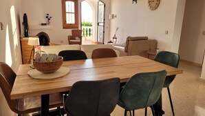 A dining area with a wooden table, chairs, and a bowl of fruit.