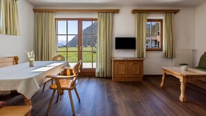 Ein Essbereich mit Tisch, Stühlen, einem Fernseher und Blick ins Freie.