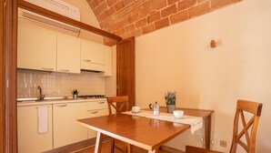 A kitchen with a wooden table, chairs, and a tiled backsplash. - Studio Apartment "Pianosa" with Sea View, Garden, Wi-Fi & Shared Pool (Piombino)