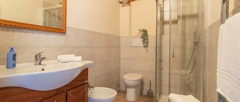 Ein Badezimmer mit Waschbecken, Bidet, Toilette und einer gläsernen Duschkabine.