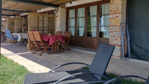 Eine Terrasse im Freien mit überdachtem Tisch und Stühlen, einer Ziegelwand und einem Holzzaun.