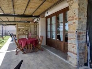A covered patio with a table and chairs, a brick wall, and a metal gate.