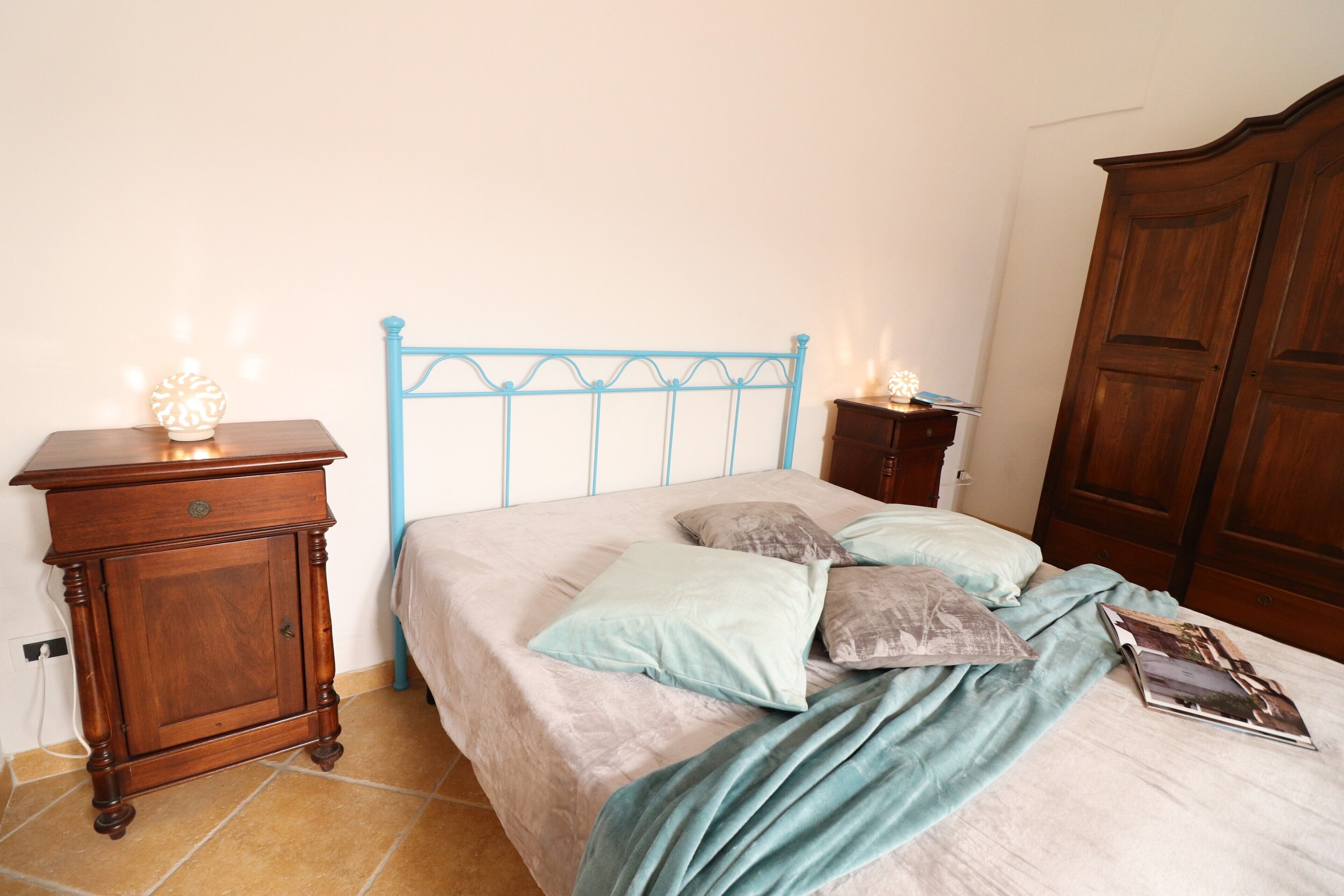 Un dormitorio con una cama, una mesita de noche de madera, un aparador y un armario.
