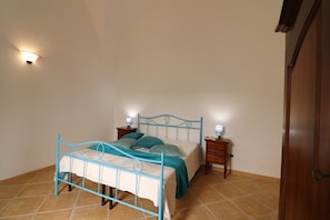 Une chambre à coucher avec un lit, des tables de chevet et un luminaire fixé au mur.