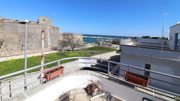 A balcony with a view of a historic fort, a marina, and a clear blue sky.
